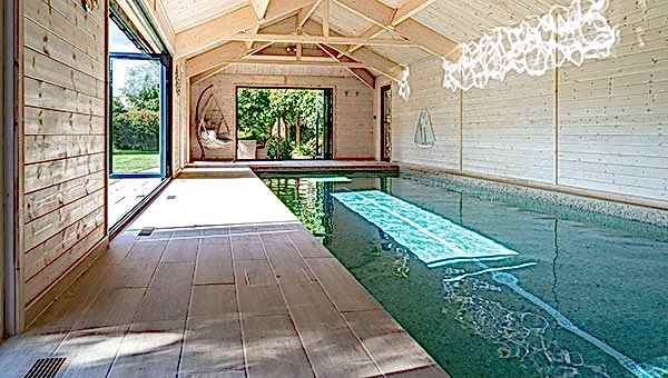 Indoor swimmign pool with bifold doors letting in sunligt