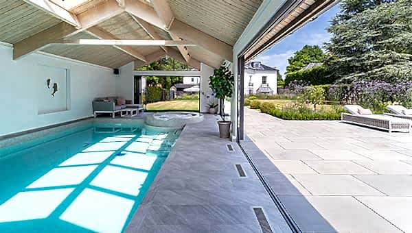 Indoor swimmign pool taken from inside the pool house, on the right the bifold doors are wide open.